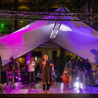Chanteuse et musiciens sur scène sous une tente éclairée en violet lors d'un événement à La Réunion